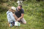 Father and daughter reading a map together in an alpine meadow