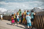 Children on a wooden viewing platform looking out at the mountains
