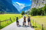Three children on bikes raising their arms on a road through the Lauterbrunnen valley