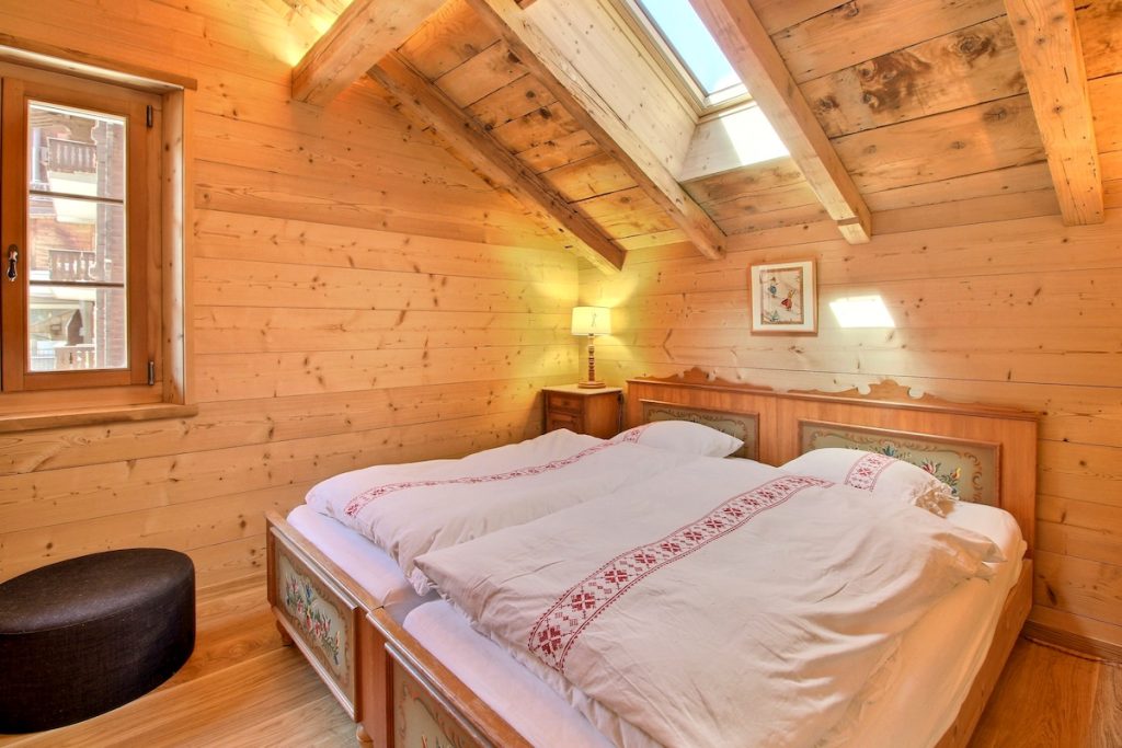 Chambre mansardée avec lit en bois peint et velux au chalet familial de Champéry