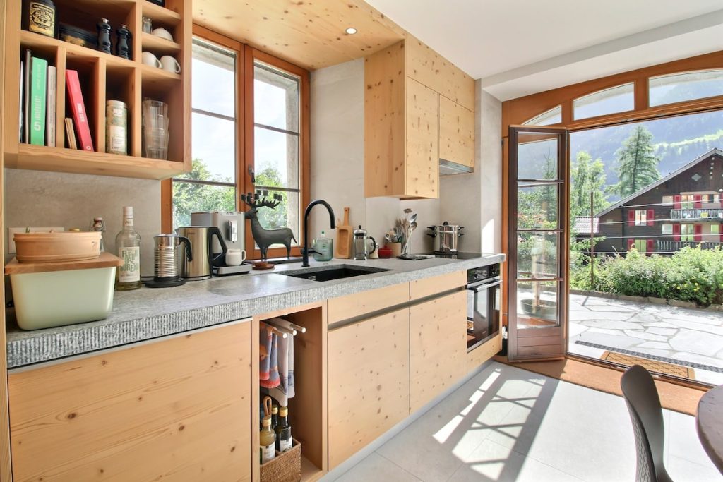 Cuisine en bois avec plan de travail en granit et portes sur la terrasse au chalet de Champéry