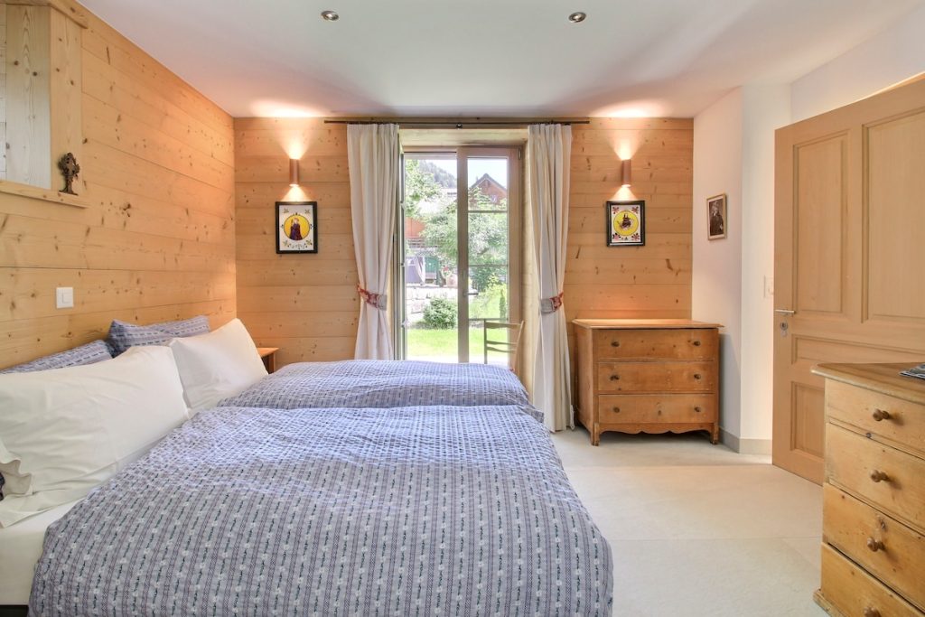 Chambre de plain-pied avec lit double et porte-fenêtre sur la pelouse au chalet de Champéry