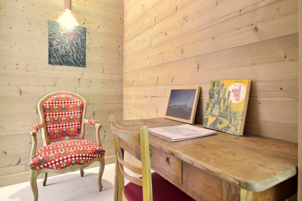 Bureau avec fauteuil rouge à motifs et affiches encadrées au chalet de Champéry