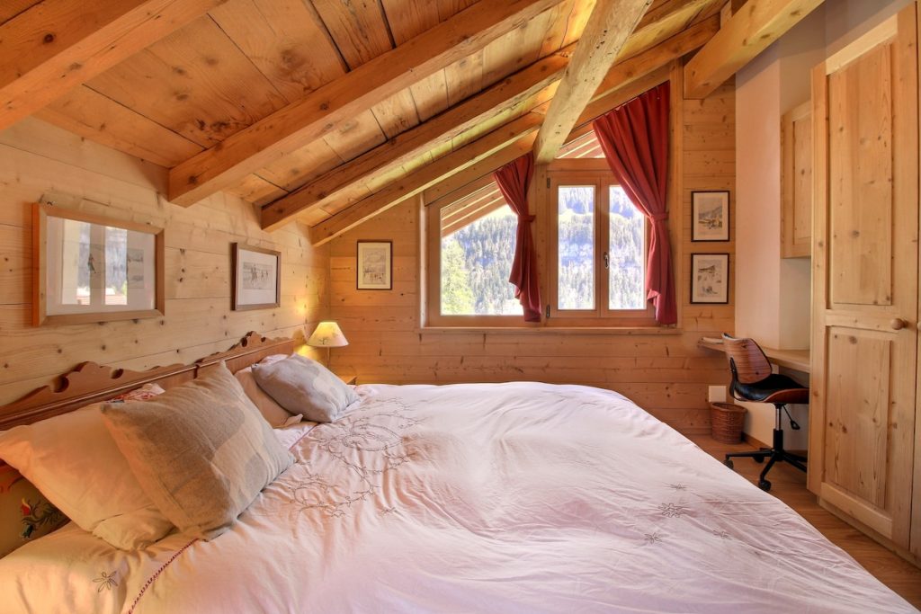 Chambre mansardée avec lit double sous les poutres au chalet de Champéry