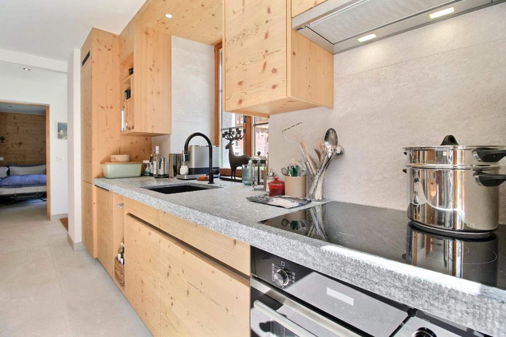 Cuisine en bois avec plan de travail en granit et plaque à induction au chalet du camp familial