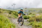 Child riding a flow trail below a chairlift in the mountains
