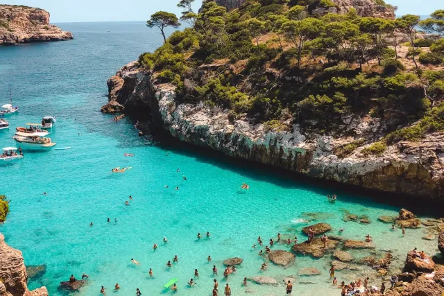 Turquoise Mediterranean cove with a sandy beach and moored boats seen from above