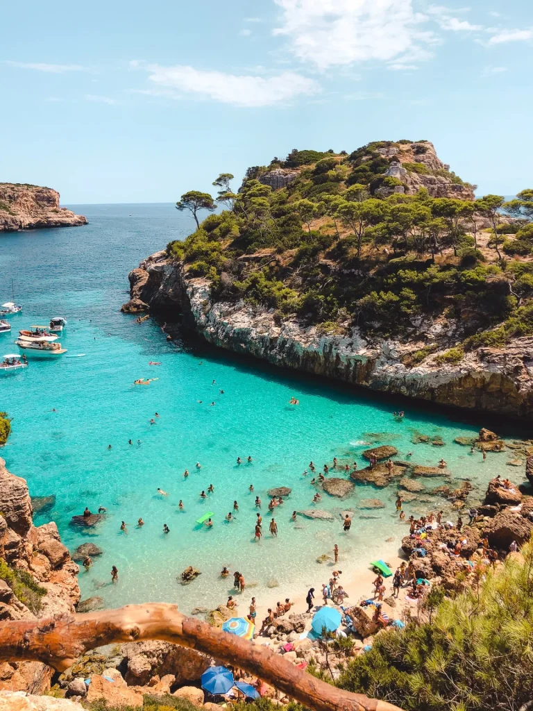 Turquoise Mediterranean cove with a sandy beach and moored boats seen from above